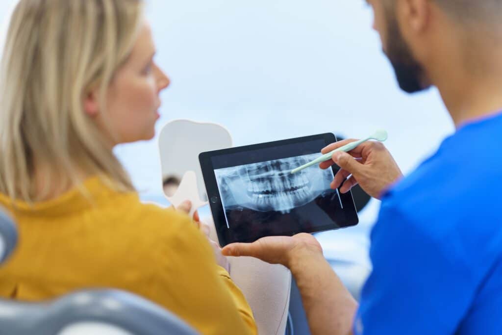Rear,View,Of,Dentist,Showing,X-ray,Scan,At,Digital,Tablet